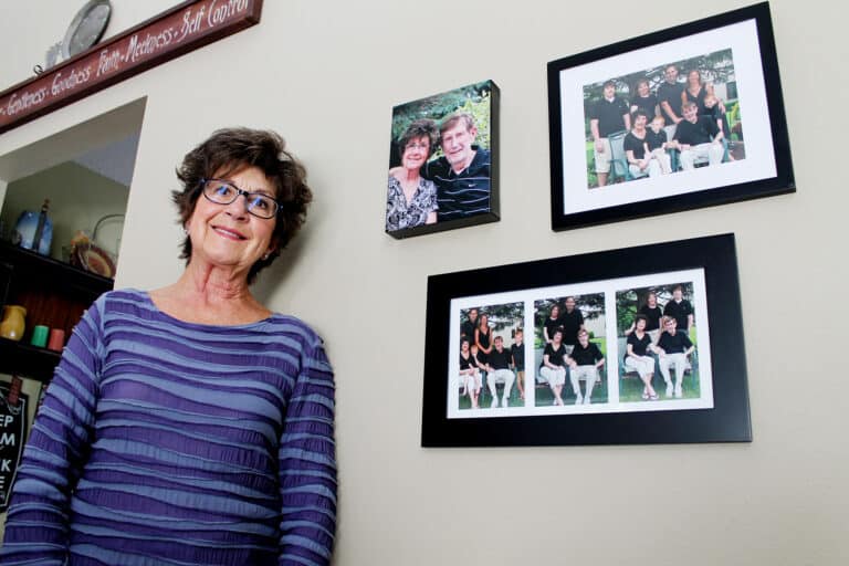 woman smiling next to family photos