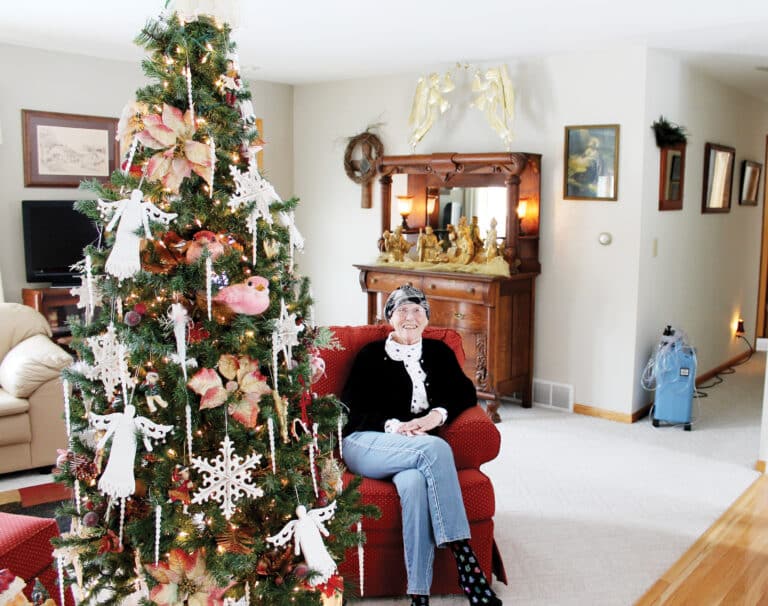 elderly woman sitting in cushioned chair next to a Christmas tree