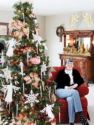 a woman sitting in a cushion chair next to a Christmas tree