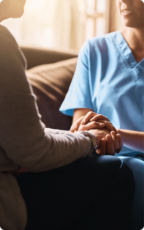 nurse and patient embracing hands talking on a couch
