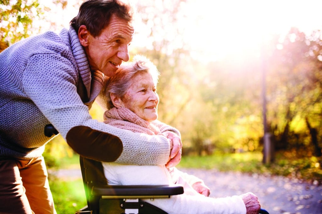 Senior man and woman in wheelchair in autumn nature.